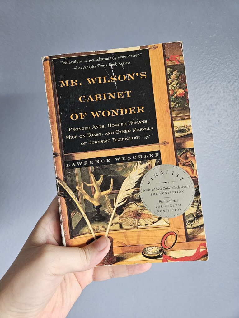 Hand holding book: Mr. Wilson's Cabinet of Wonder